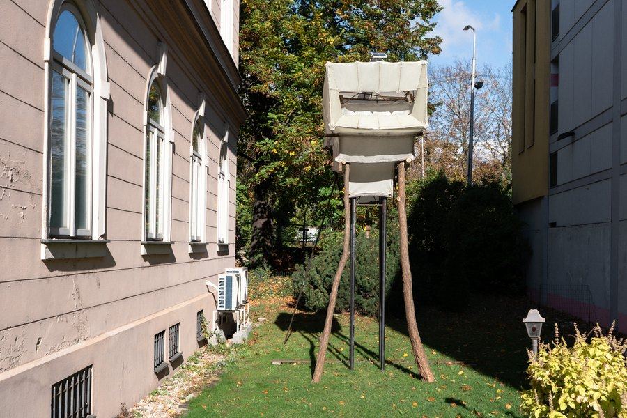 Objekt potiahnutý laminátom na drevených nohách vo dvore galérie
